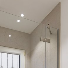 Eine moderne Dusche mit einem großen, runden Duschkopf und eleganten, gläsernen Wänden in einem hellen Badezimmer.