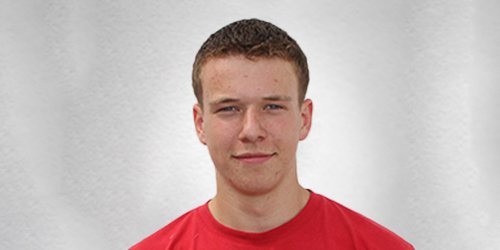 Ein junger Mann mit kurzen, braunen Haaren trägt ein rotes T-Shirt und blickt direkt in die Kamera.