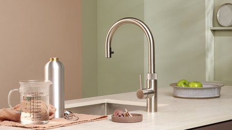 Eine moderne Küchenspüle mit einem eleganten Wasserhahn, daneben ein Messbecher und eine Edelstahlflasche.