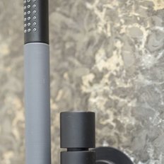 Ein eleganter Wasserhahn aus mattem Schwarz und Grau, montiert an einer strukturierten Steinwand, strahlt modernes Design aus.