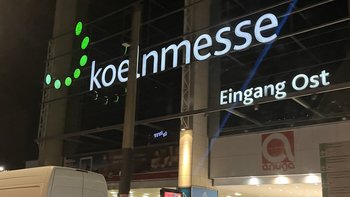 Die beleuchtete Fassade des Eingangs Ost zur Koelnmesse zeigt das moderne Design des Messegeländes bei Nacht.