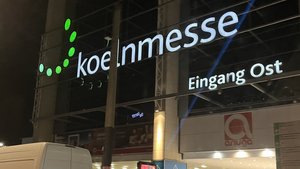 Die beleuchtete Fassade des Eingangs Ost zur Koelnmesse zeigt das moderne Design des Messegeländes bei Nacht.
