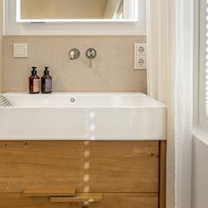 Ein modernes Badezimmer mit einem eleganten Waschbecken aus weißem Keramik und einem Holzschrank darunter.