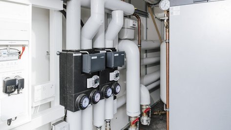 Komplexe Rohrleitungen und Steuergeräte in einem modernen Technikraum, die für die effiziente Energieverteilung zuständig sind.