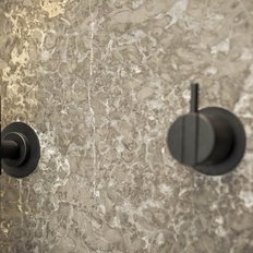 Eine moderne Duscharmatur mit einem eleganten schwarzen Design, montiert an einer strukturierten, hellen Wand.