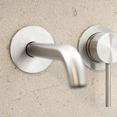 Ein modernes, elegantes Wasserhahn-Design aus Edelstahl, montiert an einer hellen, strukturierten Wand.