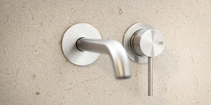 Ein modernes, elegantes Wasserhahn-Design aus Edelstahl, montiert an einer hellen, strukturierten Wand.