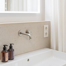 Ein elegantes Badezimmer mit einem modernen Waschbecken, einem großen Spiegel und zwei Seifenspendern auf der Ablage.