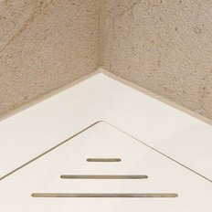 Die Ecke eines Raumes zeigt eine helle Wand mit feiner Textur und einen weißen Bodenablauf in einem modernen Design.