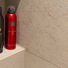 Zwei Flaschen Duschschaum stehen auf einem Regal in einem modernen Badezimmer, eine schwarz und eine rot.