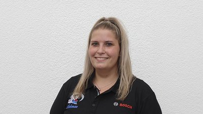 Die Frau hat eine entspannte Ausstrahlung, ihre Haare sind locker gebunden, während sie in die Kamera lächelt.