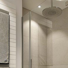 Ein modernes Badezimmer mit einer eleganten Dusche und einem großen, runden Duschkopf, der an der Decke hängt.