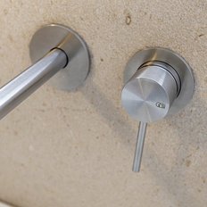 Ein eleganter Wasserhahn aus Edelstahl, der an einer sandfarbenen Wand montiert ist, strahlt modernes Design aus.