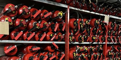 Eine Wand voller roter Feuerlöscher, ordentlich in Regalen gestapelt, bereit für den Einsatz in Notfällen.