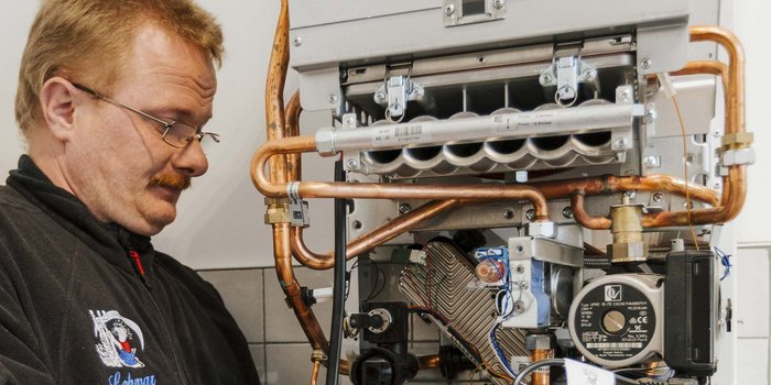 Ein Techniker arbeitet konzentriert an einer Heizungsanlage, um sicherzustellen, dass alle Rohre korrekt installiert sind.