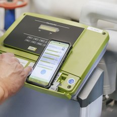 Ein Techniker bedient ein modernes Messgerät mit einem Smartphone, das Daten anzeigt und analysiert.