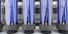 Eine Reihe von transparenten Röhren mit blauen und silbernen Elementen, die in einer industriellen Umgebung angeordnet sind.