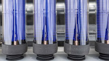 Eine Reihe von transparenten Röhren mit blauen und silbernen Elementen, die in einer industriellen Umgebung angeordnet sind.
