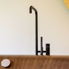Ein eleganter schwarzer Wasserhahn steht neben einer Holzoberfläche, die eine warme, einladende Atmosphäre schafft.