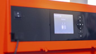Ein orangefarbenes Gerät mit einem digitalen Bildschirm zeigt die Kesselfolge an, mit zwei Kesseln in der Anzeige.