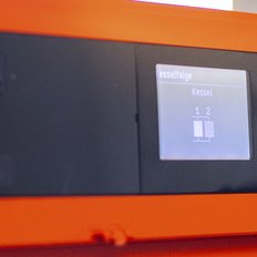Ein orangefarbenes Gerät mit einem digitalen Bildschirm zeigt die Kesselfolge an, mit zwei Kesseln in der Anzeige.