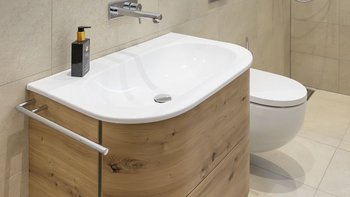 Ein modernes Badezimmer mit einem eleganten Waschbecken aus Holz und einem weißen WC, das eine stilvolle Atmosphäre schafft.