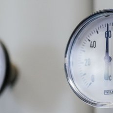 Zwei präzise Temperaturmessgeräte zeigen Werte zwischen 0 und 120 Grad Celsius an, montiert an einer hellen Wand.