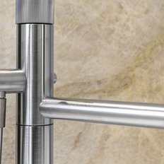 Ein eleganter, moderner Wasserhahn aus Edelstahl, der an einer hellen, strukturierten Wand montiert ist.
