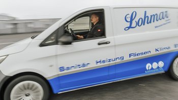 Der Fahrer eines Lieferwagens mit dem Logo 'Lohmar' ist unterwegs, während die Umgebung verschwommen ist.