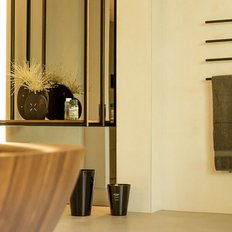 Ein modernes Badezimmer mit einem eleganten Holzwaschbecken und stilvollen schwarzen Handtuchhaltern an der Wand.