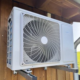 Eine Klimaanlage ist an einer Holzwand montiert, mit einem großen Ventilator, der für frische Luft sorgt.