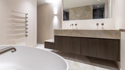 Ein modernes Badezimmer mit einer eleganten Holzwaschtischplatte und zwei Wasserhähnen, die an einer hellen Wand montiert sind.