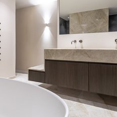 Ein modernes Badezimmer mit einer eleganten Holzwaschtischplatte und zwei Wasserhähnen, die an einer hellen Wand montiert sind.