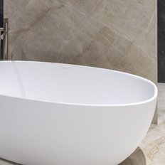 Eine elegante, freistehende Badewanne aus weißem Material steht in einem modernen Badezimmer mit marmoriertem Boden.