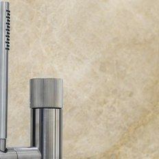 Ein eleganter Wasserhahn aus Edelstahl mit einem modernen Design, der vor einer marmorierten Wand platziert ist.