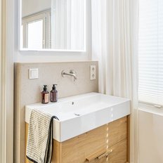 Ein modernes Badezimmer mit einem eleganten Waschbecken aus Keramik und einem Holzschrank, der eine warme Atmosphäre schafft.