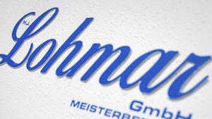 Das Logo von Lohmar GmbH in kräftigem Blau auf einer weißen, leicht feuchten Oberfläche, die die Schrift hervorhebt.