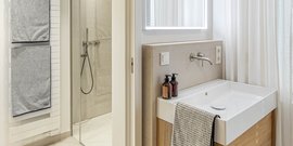 Ein modernes Badezimmer mit einer eleganten Dusche und einem stilvollen Waschbecken aus weißem Keramik und Holz.